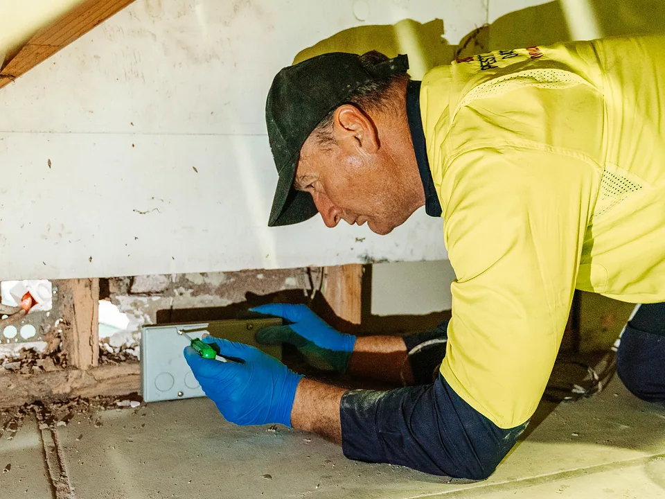 Bug Free technician opening a roof void access hatch to inspect